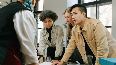 Diverse group of people discussing something over a table.