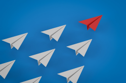 white paper airplanes with one red paper airplane on a blue background
