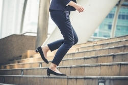 A woman in a pantsuit and heels climbing stairs