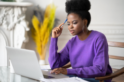 A woman sits across from computer.