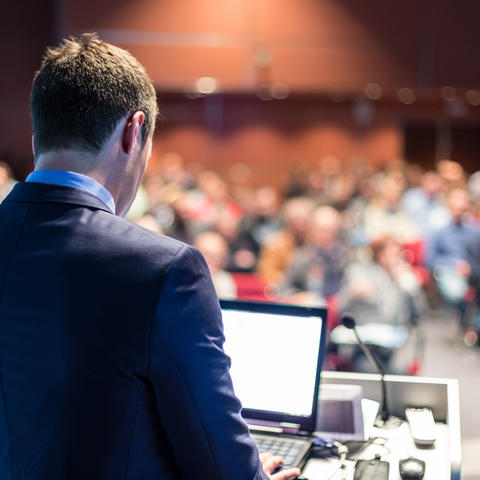 Man standing at podium facing audience.